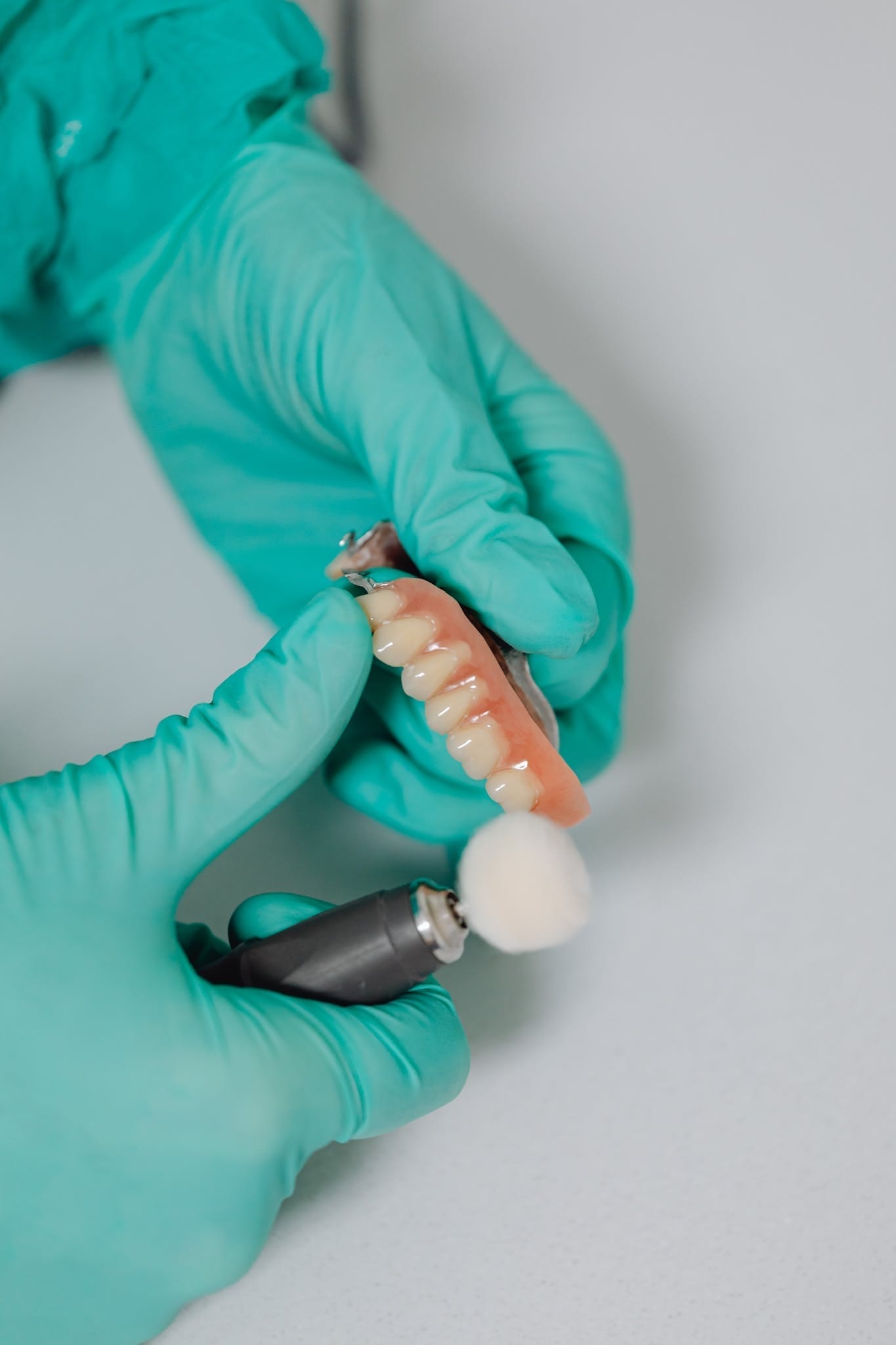 A Close-Up Shot of a Person Polishing a Denture. Ivy Lane Dentistry offers full and partial dentures in San Antonio, TX.