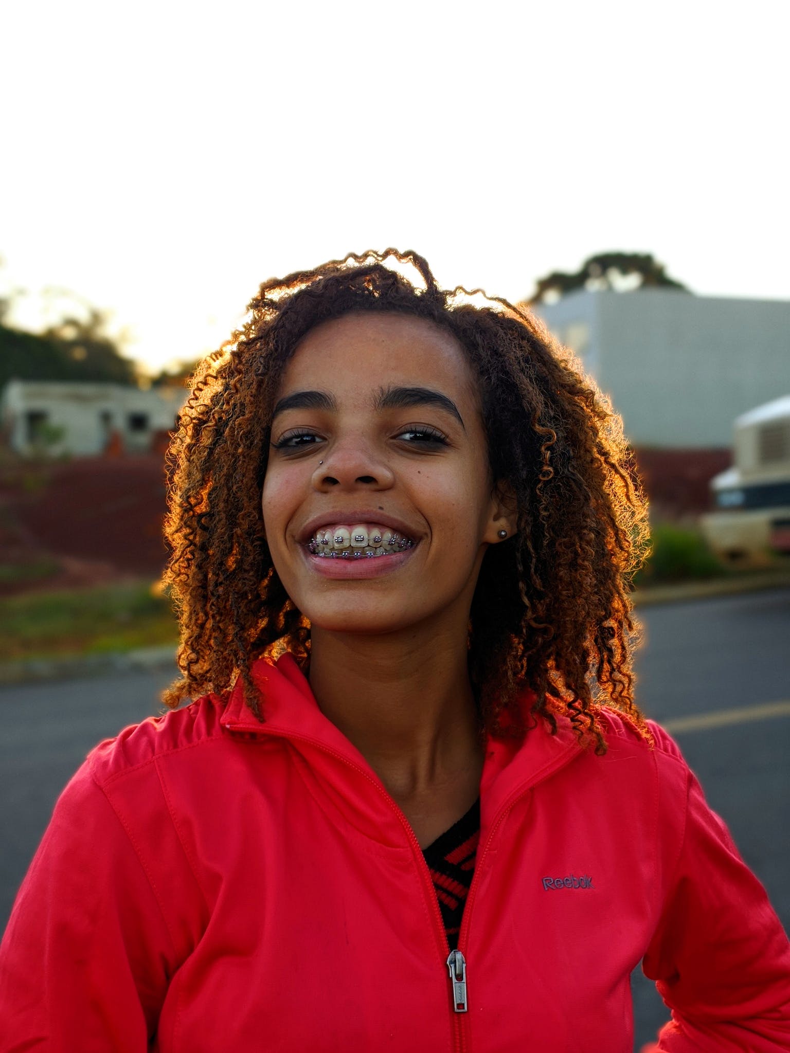 Woman in Red Jacket Smiling. Ivy Lane Dentistry offers traditional braces for adults and children in San Antonio, TX. 