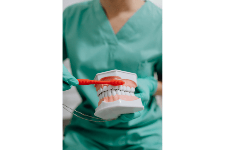 Selective focus photo of a dentist demonstrating how to brush teeth